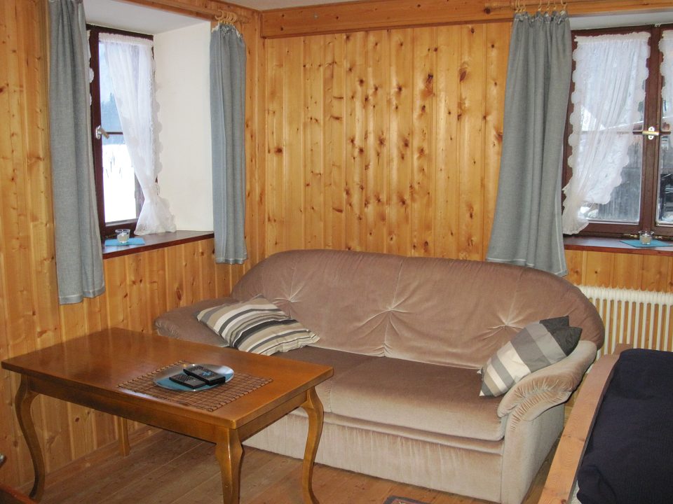 Wohnraum mit Sofa, Couchtisch und Holzvertäfelung